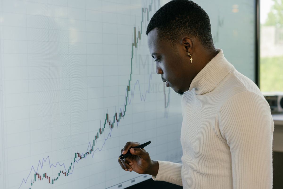 Black quantitative economic and data analyst inspecting econometric trend models on telemetry screen